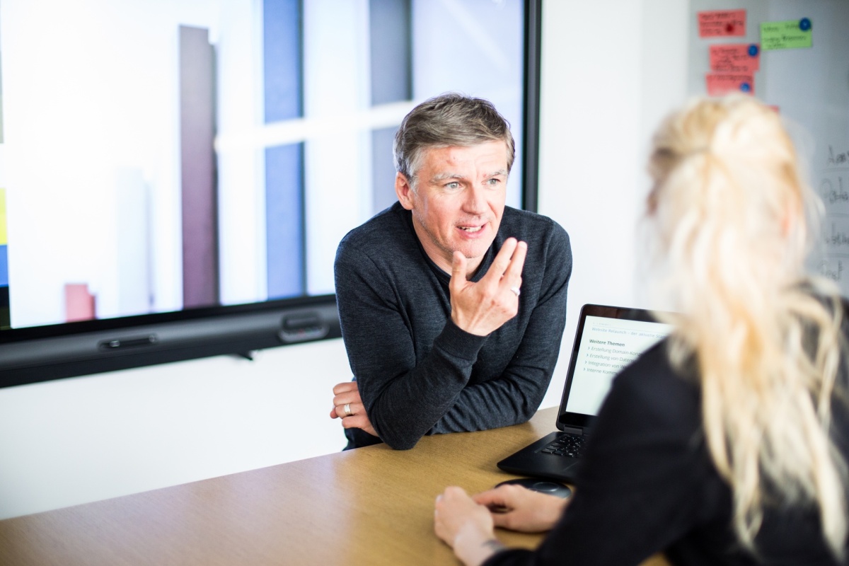 A male adessi explaining something in a meeting